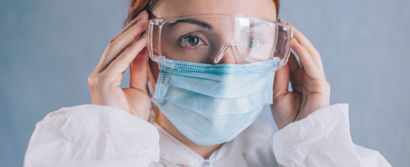 Female doctor puts on safety glasses, close-up of face.