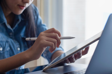 Young asian positive woman work on tablet computer.