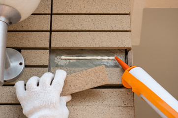 man hand holding and using glue gun ( silicone tube or manual caulking gun ) with polyurethane or...