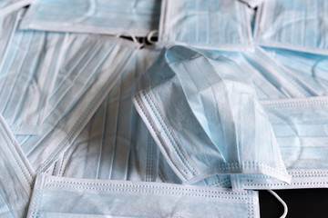 Protective masks on black background. A used surgical mask on a bed of unused surgical masks. Medical PPE.