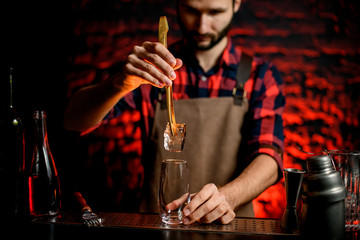 bartender put to glass large piece of ice