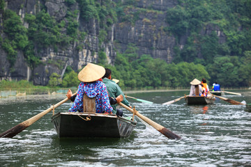 kobieta wiosłująca stopami przewożąca turystów po wietnamskiej rzece
