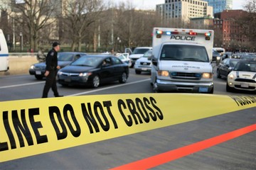Polizeifahrzeug und Polizist im Verlehr hinter gelber Polizeiabsperrung in einer Stadt (Boston, MA,...