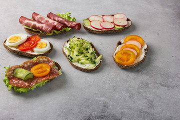 Open sandwiches on rye bread with cream cheese, ham, egg, radish, tomato, cucumber.