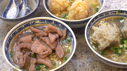 Eating Hong Kong Cantonese wonton beef and meat ball soup noodle