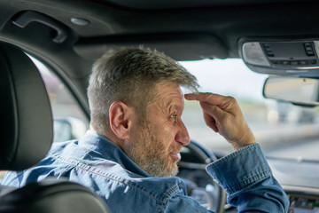 Profile of a very angry and visibly annoyed car driver showing his rage by making an unfriendly...