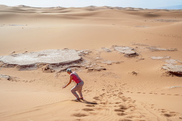 Woman sand boarding on Sahara Desert down the dune, Africa