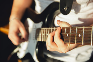 Fototapeta premium Caucasian musician playing guitar during online concert at home isolated and quarantined. Using camera, laptop, streaming, recording courses. Concept of art, support, music, hobby, education.