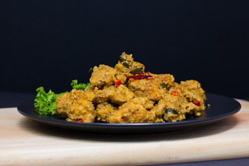 Homecooked Buttermilk Chicken with Lemon in a black background. Placed on the wooden cutting board.