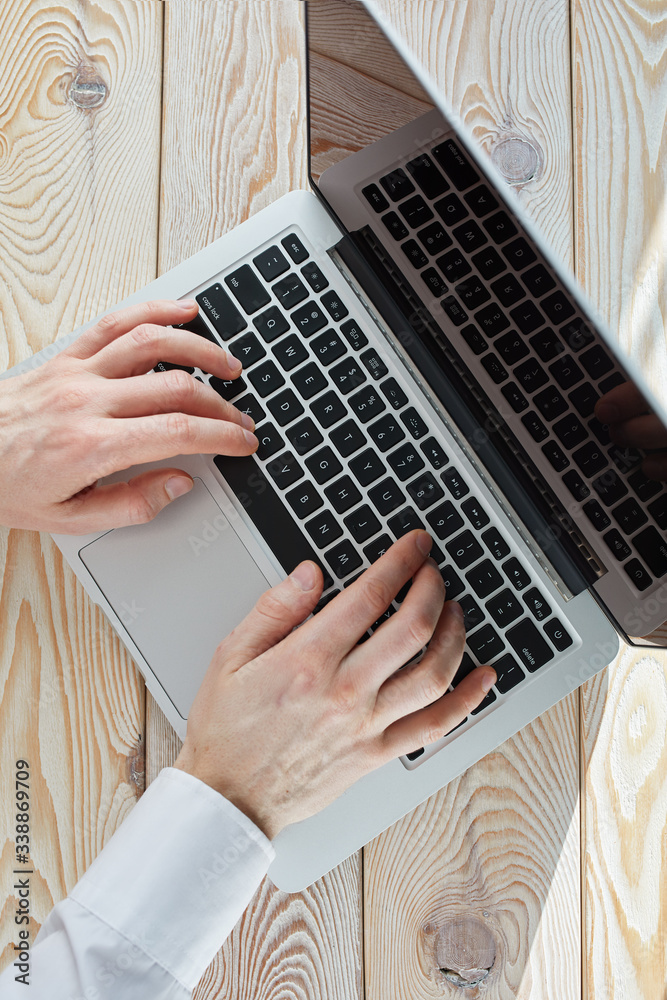 Poster top view of man's hands typing on laptop in sunny day. coworking or working at home concept image.