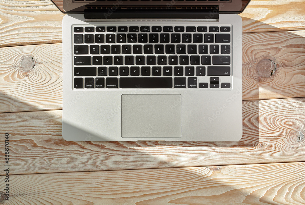 Aufkleber Top view of laptop on loft-style table in sunny day. Coworking or working at home concept image.