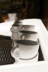 Closeup row of white empty coffee cups against blurred background. Shallow focus.