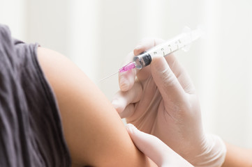 close up doctor's hand injecting for vaccination in the shoulder woman patient.Vaccine for protection HPV (Human Papillomavirus) infection.Vaccination for coronavirus treatment.