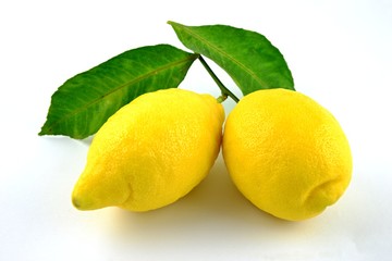 Two yellow lemons with green leaves on white background. Fresh citrus.
