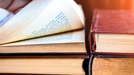 a stack of books . hand turns over the pages of an old book .