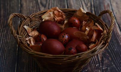 Naturally Eggs painted with onion peel and quail feathers in a wicker basket.Eco paint. Happy Easter card. Flat lay. old eco-friendly method. Copy space for greeting text