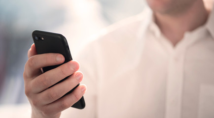 Close-up of a business man holding and looking at a smartphone