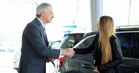 Car dealer giving a handshake to a young woman