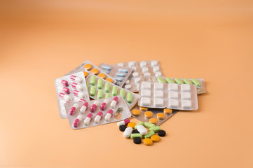 A pile of multi-colored pills lie on an orange background in the center.