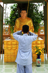 Azjata modlący się przed posagiem Buddy