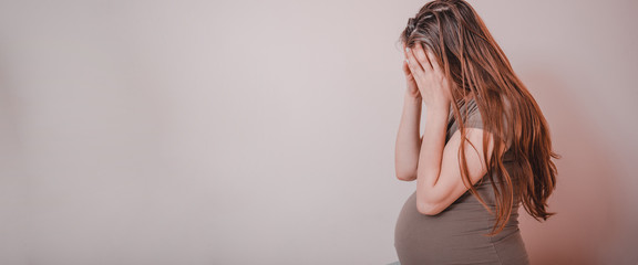 Sad woman crying while sitting on bed in her bedroom. Stressed pregnant woman or mother problems.