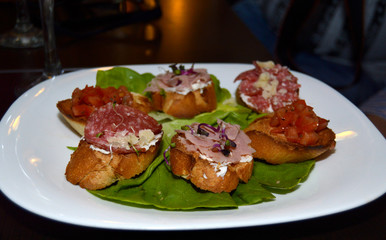Close up shot of Italian style bruschetta, various mixed meat and vegetables on toasted slices of bread, healthy food for brunch or lunch, cuisine recipe from Italy