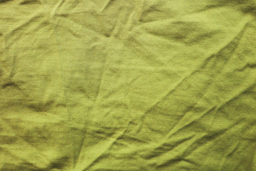 Crumpled old faded yellow fabric texture. Creased used cloth background canvas, messy wavy clothes material detail, old worn pale yellow colour apparel close up top view