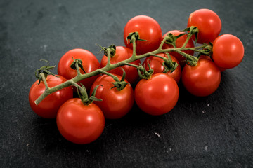 rote Tomaten an einer Rispe auf einer Schiefertafel