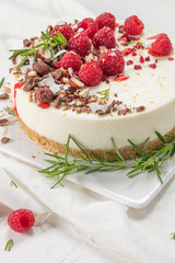 Cheesecake with raspberriees, chocolate, hazelnuts and rosemary leaves on kitchen coutertop