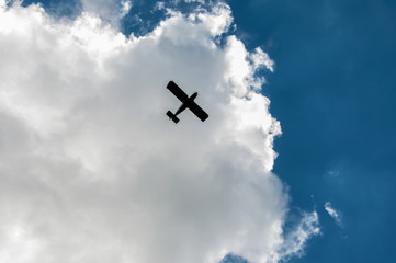 Small plane silhouette in cloudy sky