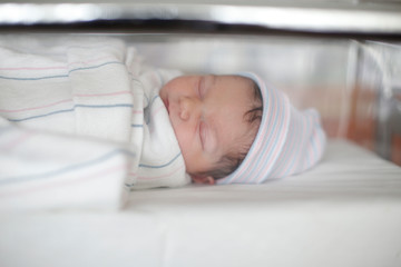 A newborn sleeps in her hospital bassinet