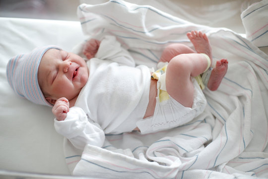 A Newborn Infant In Diaper Sleeps In Her Hospital Bassinet