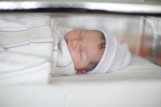 A Newborn Sleeps In Her Hospital Bassinet