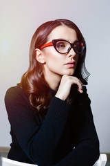 Portrait of young brunette woman with a healthy clean skin. Young beautiful business woman in stylish glasses and white shirt posing in studio. 