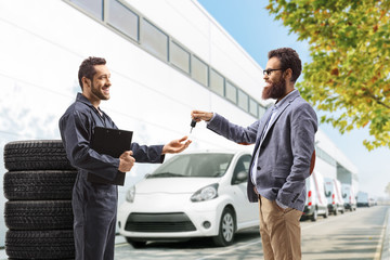 Customer giving a car key to an auto mechanic