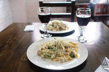 lunch for two penne pasta with vegetables and glass of wine