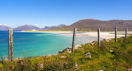 Obraz premium White sand beach seen through a fence in Isle of Harris, Outer Hebrides, Scotland / UK