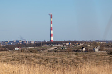 Energy heat power station pipe with red white stripes. Europe, Ukraine countryside, clear sky landscape with air pollution smoke tower