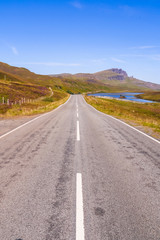 Fototapeta na wymiar Scottish landscapes: road at Isle of Skye with the Old Man of Storr in the distance
