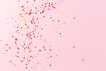 Multicolored confetti on pink background.