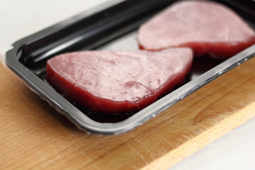 Raw tuna steak in disposable plastic packing box