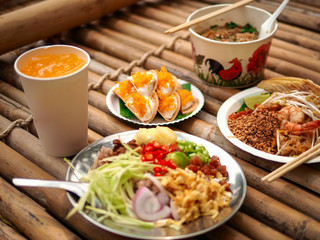 Many Thai food is placed on the bamboo table.