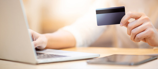 Fototapeta premium Male customer hand using credit card for online shopping during quarantine at home. Male shopper buying goods and making payment with electronic banking. Financial technology concept