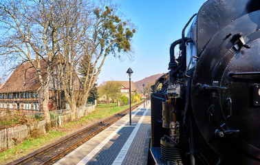 Steam locomotive drives through the streets of the city of Wernigerode past the houses. Dynamic through motion blur.