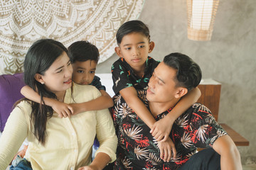 Obraz premium Southeast Asian family spending time at home. Happy Indonesian or malasian parents and children laying in bed having fun together