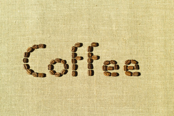 Word coffee written with brown coffee beans seen from above, headline, illustration