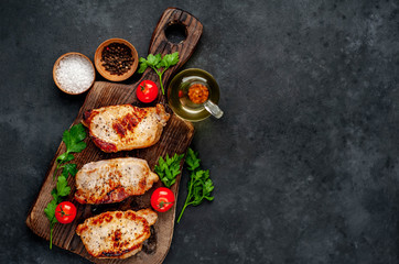 grilled pork steaks with spices on a cutting board on a stone background with copy space for your text