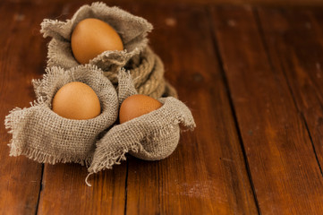 Fototapeta na wymiar Eggs stand on a burlap that stands on a brown wooden table. Top views with clear space