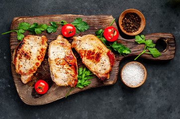 grilled pork steaks with spices on a cutting board on a stone background