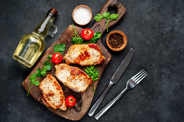 grilled pork steaks with spices on a cutting board on a stone background
